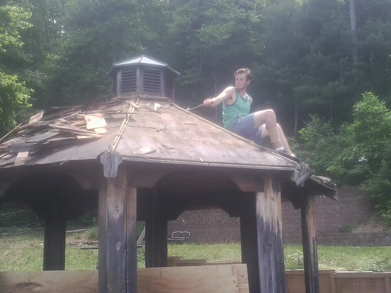 Tearing the old roof off a wooden gazebo before new shakes in Rebecca