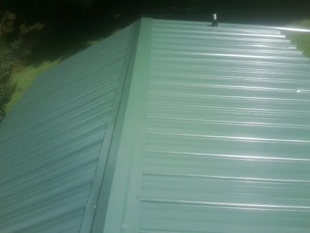 New green metal panels meeting at the ridge of a roof — Flat Roof Repair work by our crew in Rebecca