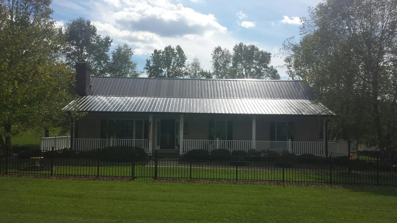 Gray metal roof on a brick ranch with a full width front porch — Gutter Guard Installation work by our crew in Rebecca
