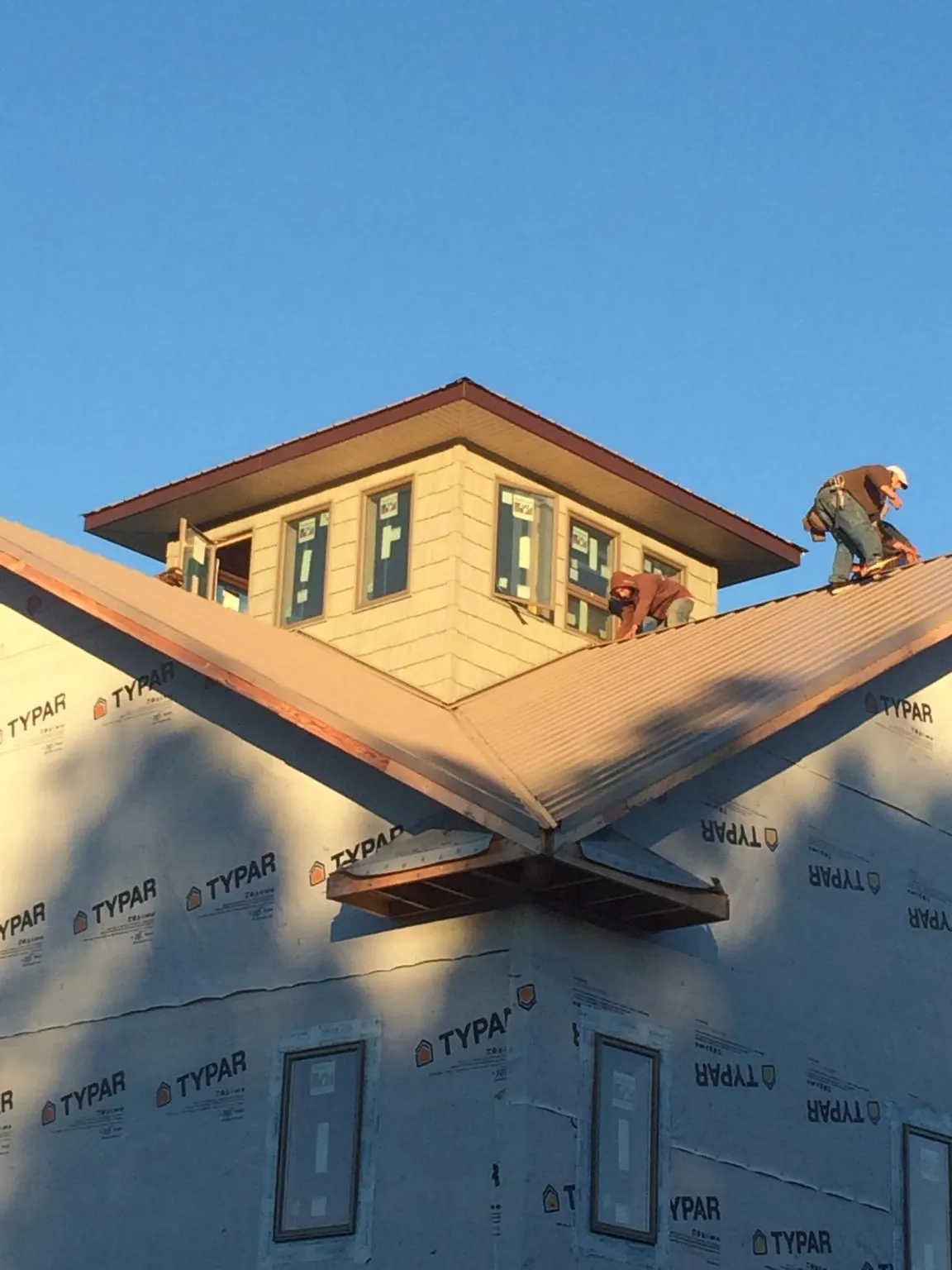 Roofers working around a rooftop cupola on a new metal roof at sunset — Roof Waterproofing in Rebecca by Roofing Brothers